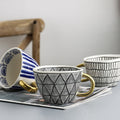 Cup with abstract geometric pattern and gold handle